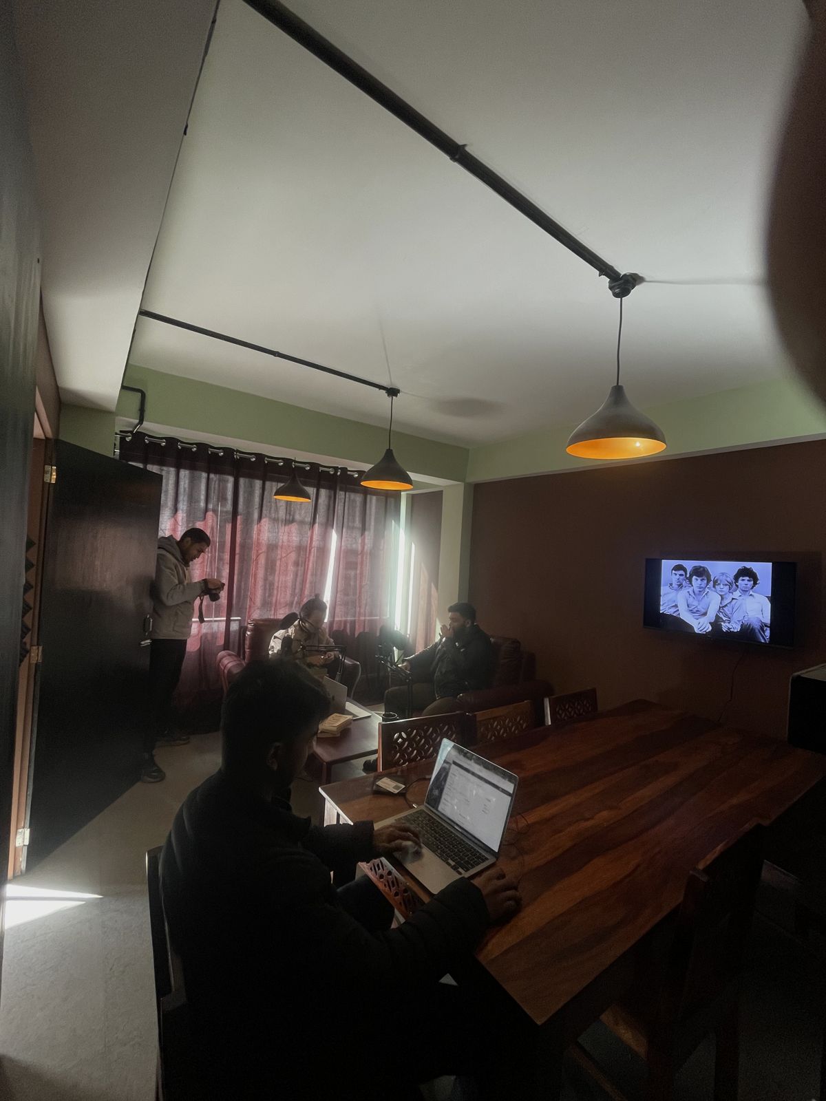 The meeting room with a long table, a laptop and a wall-mounted TV