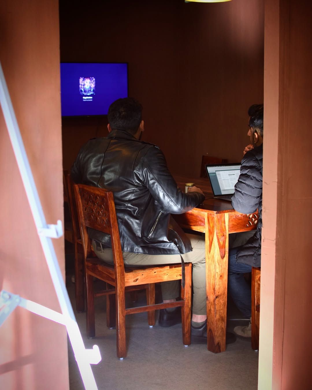 Two people at the meeting room table with a wall-mounted screen