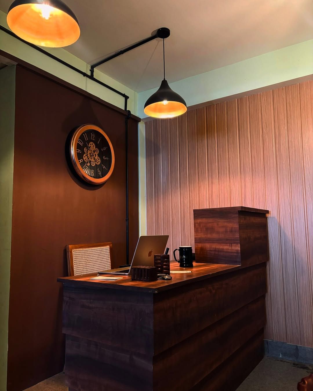 The Sanctorum front desk with a wall clock and pendant lamps