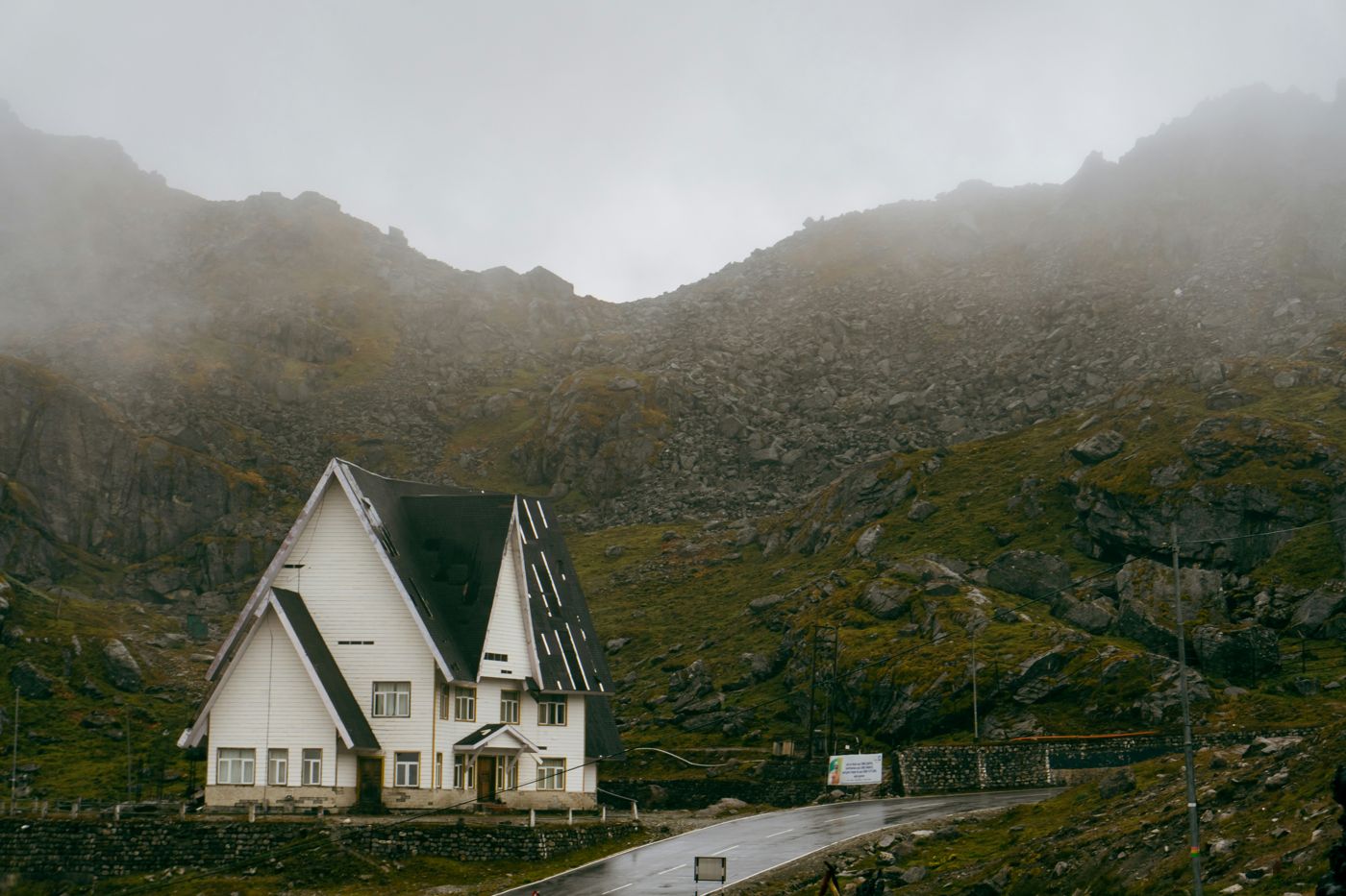 A white hut below misty green mountains on the road to Tsomgo
